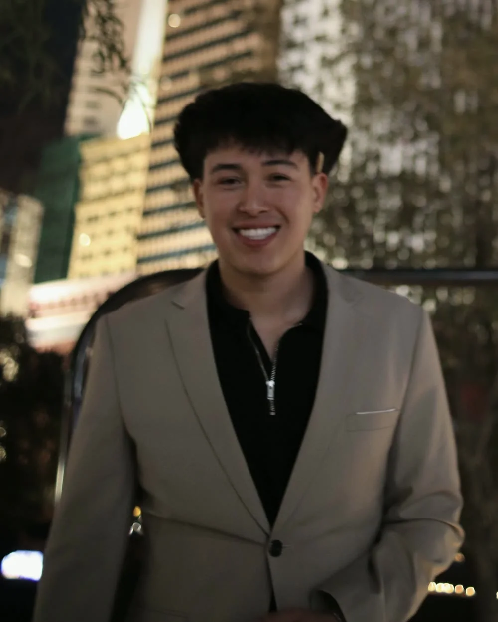 Jordan Lopez smiling outdoors at night in a light blazer
